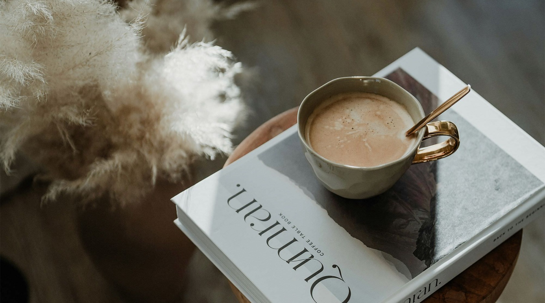 a cup of coffee on a book on a stool in a living room