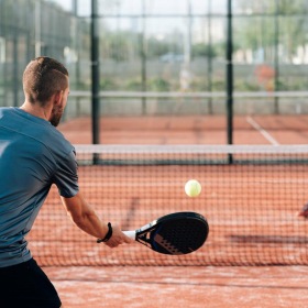a person hitting a ball with a pickleball paddle to another person